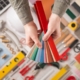 Male hands holding swatches and choosing the right color, work tools on background top view