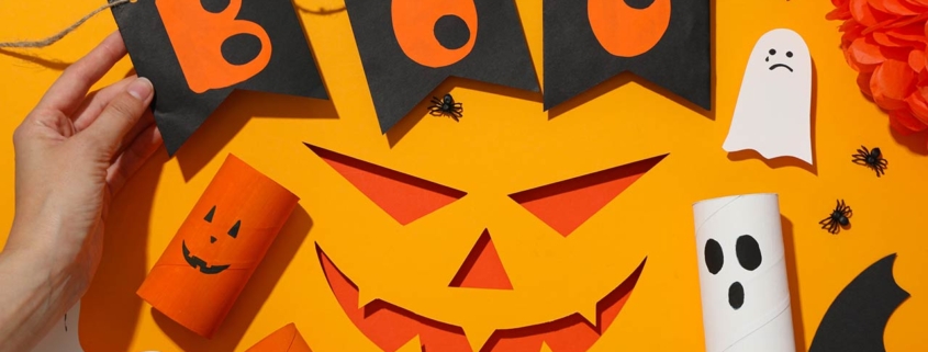 Paper decorations for Halloween on orange background, top view