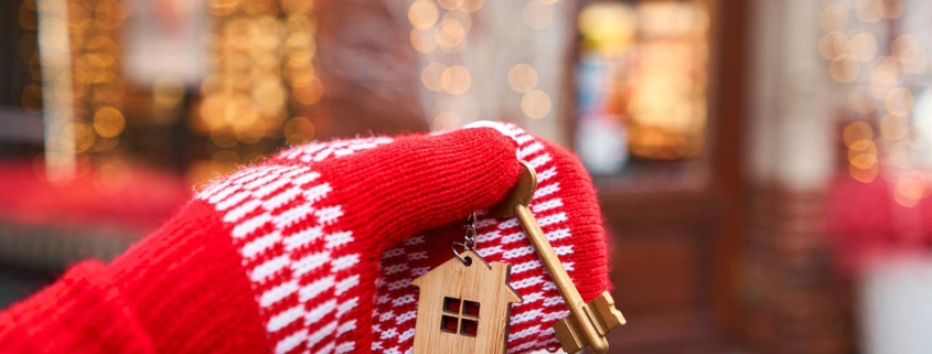 Hand in red mitten holding key with house shaped keychain